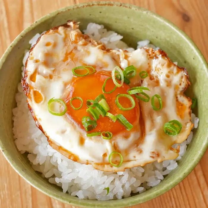 丼に盛られたご飯の上に、和風のたれで漬けた目玉焼きがのっており、小ネギがトッピングされています。