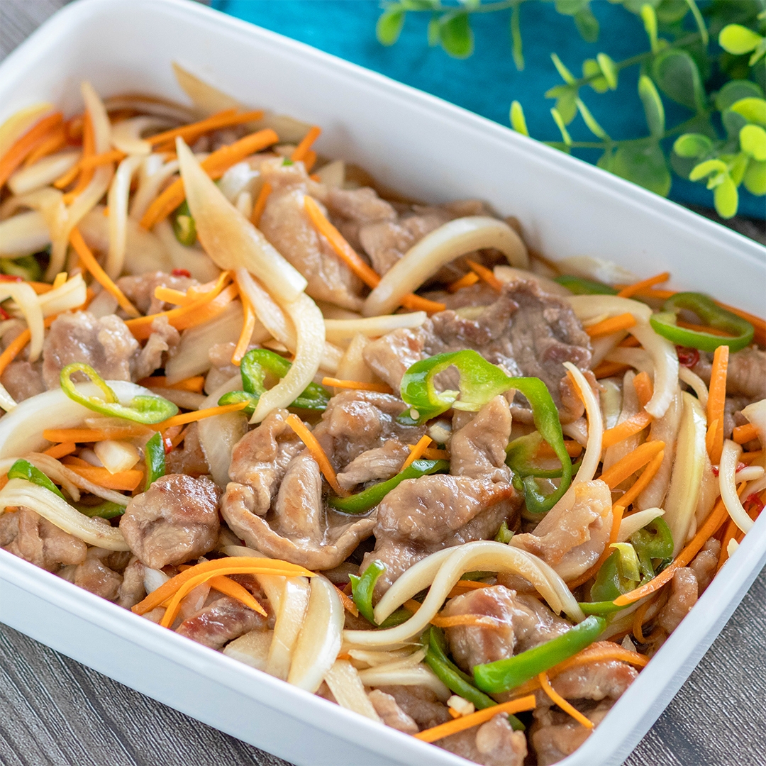 中華風肉野菜炒めが盛られた白い容器。細切り人参、ピーマン、玉ねぎが入っている。
