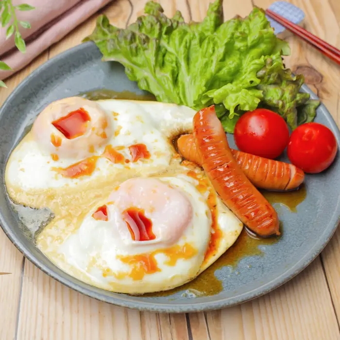 甘酢味の目玉焼きにソーセージ、トマト、レタスが添えられた朝食プレート。