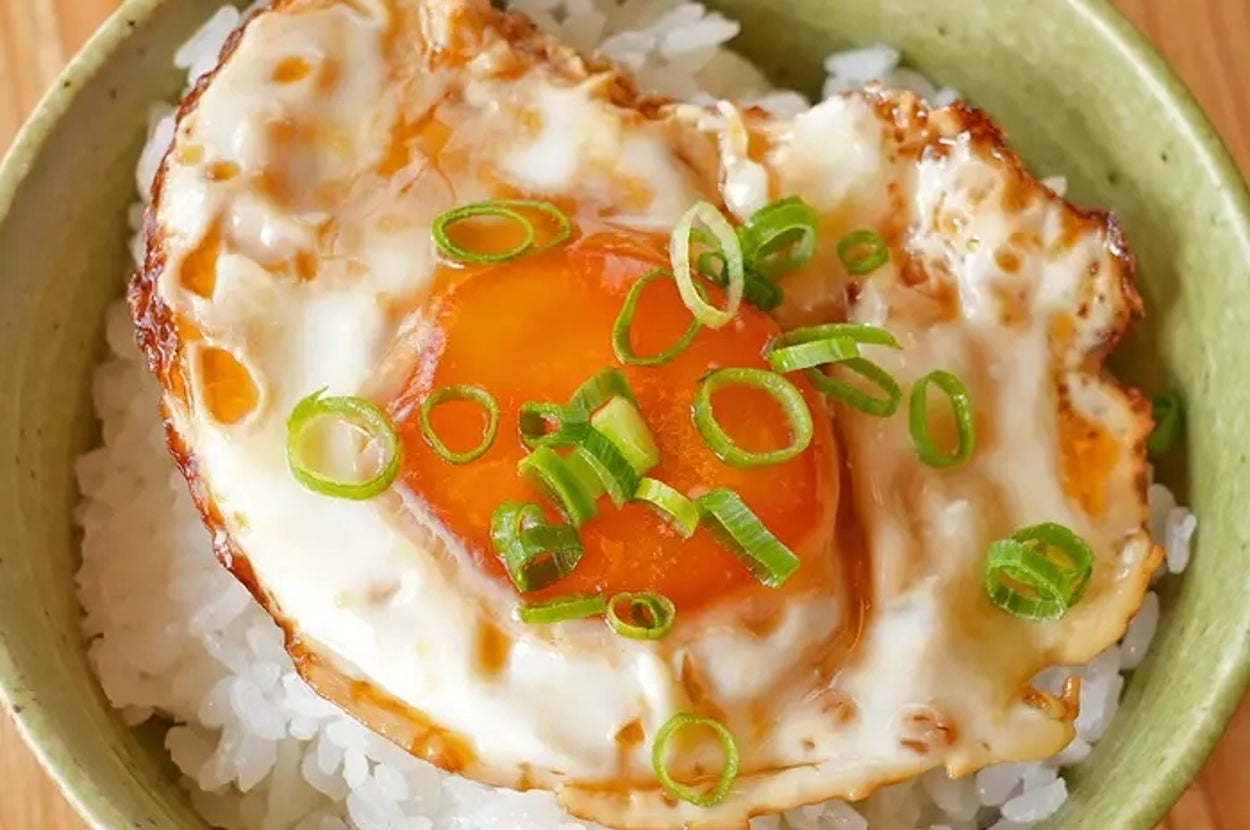 丼に盛られたご飯の上に、和風のたれで漬けた目玉焼きがのっており、小ネギがトッピングされています。