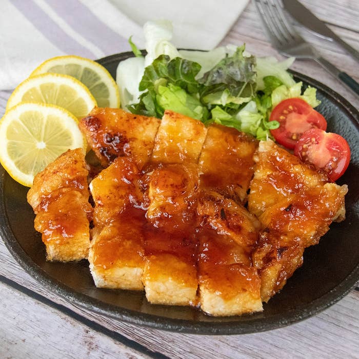 はちみつ、レモン汁、しょうゆのたれで味付けされた鶏むね肉のプレート。レモンとサラダ、ミニトマトが添えられている。