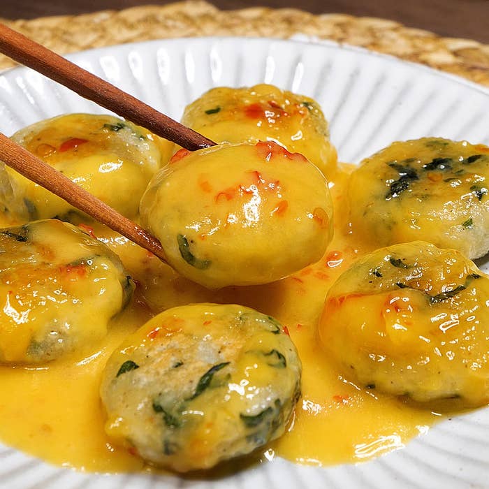 皿にソースがかかった餃子を箸で持ち上げている様子。