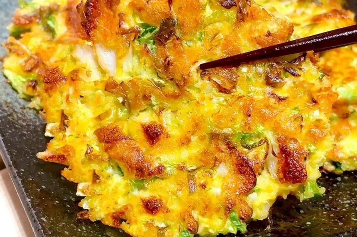 皿に盛られた具沢山のお好み焼きが箸で持ち上げられている。