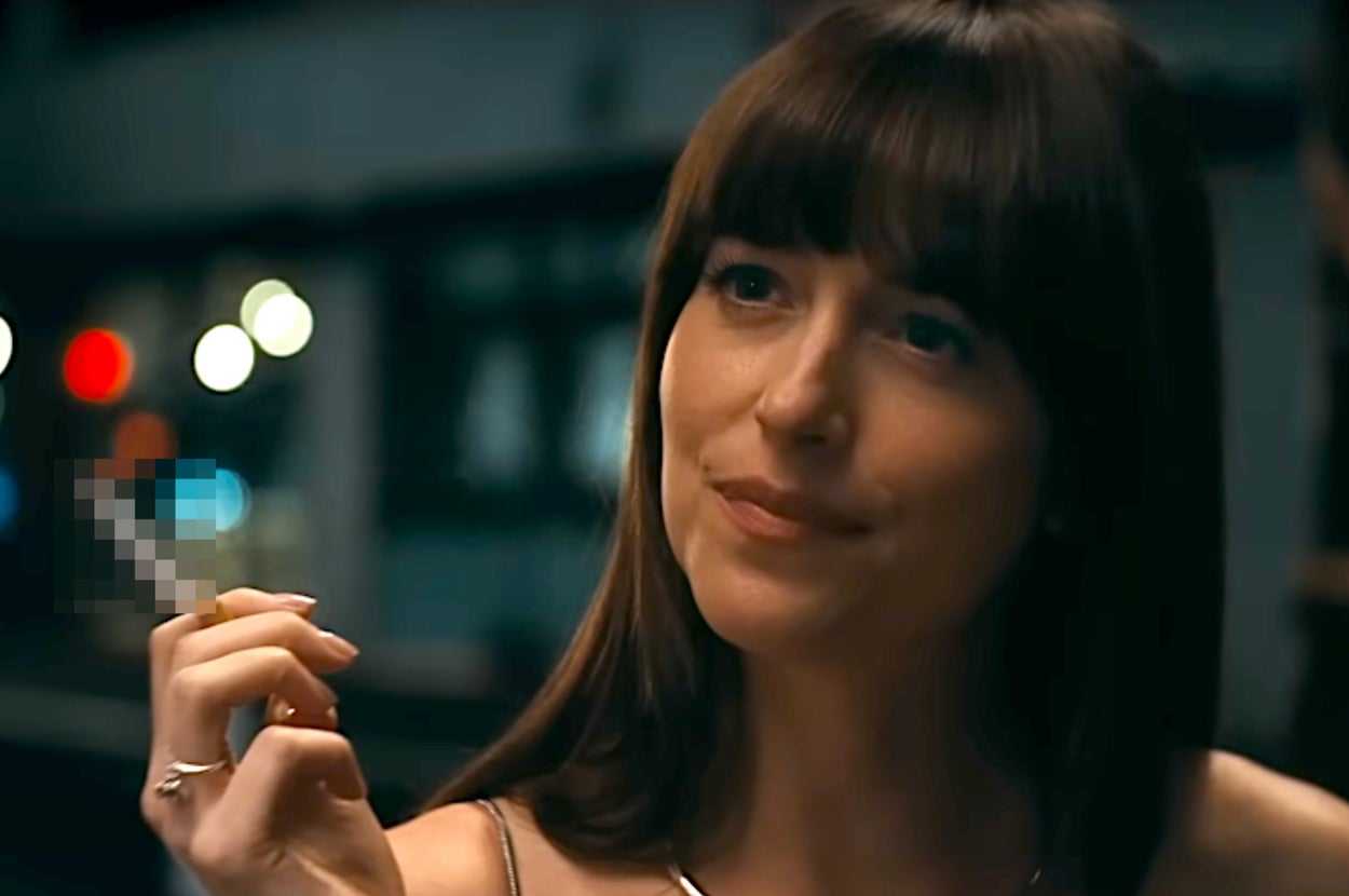 A person with long hair holds a cigarette and smiles softly, wearing a sleeveless top in a scene suggestive of intimacy or nightlife