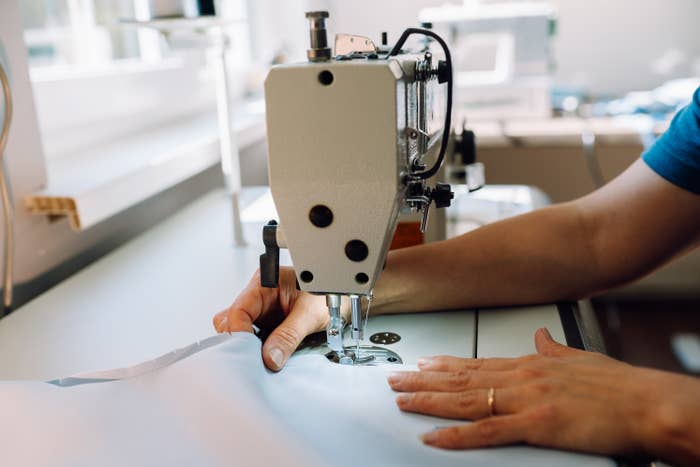 Person utilizing a sewing machine, stitching cloth successful a agleam workspace. Hands usher the worldly nether the needle