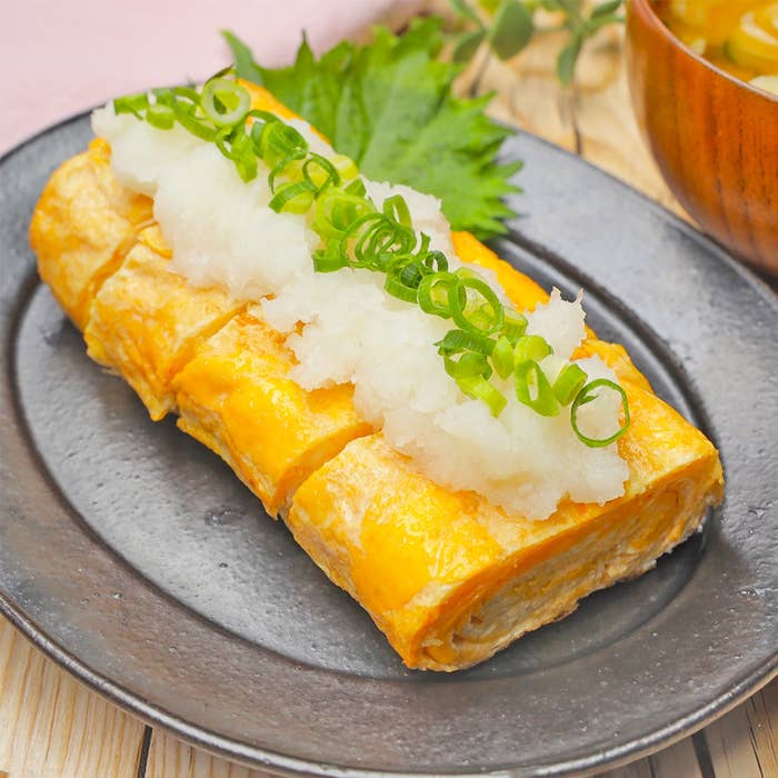 皿に盛られた厚焼き玉子の上に大根おろしとネギが載っている料理。