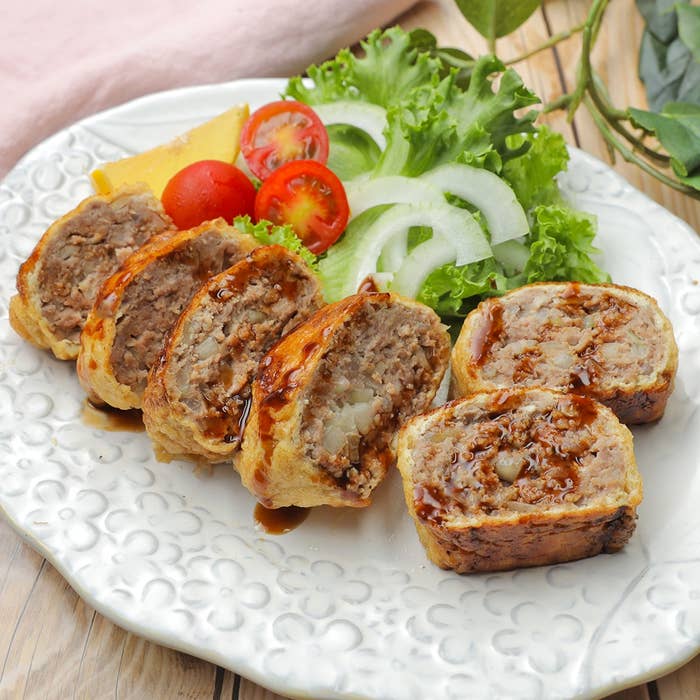 お皿に盛られたメンチカツ風の料理、添え物の野菜とソースがかかっています。