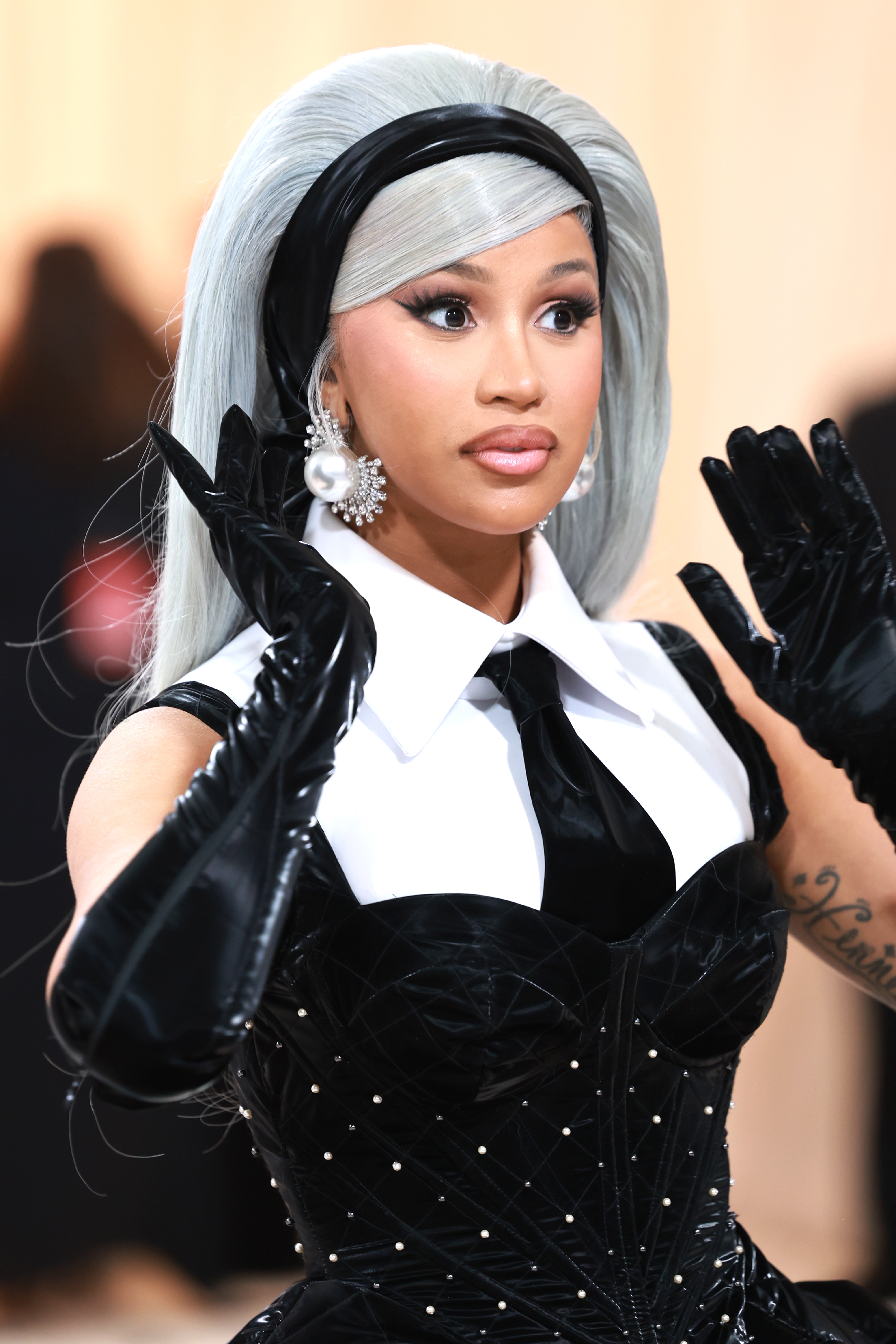 Cardi B in voluminous outfit with headband, pearl earrings, and long gloves, on red carpet