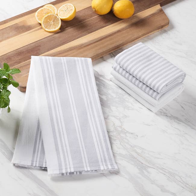 Striped room  towels displayed connected  a marble aboveground  with lemons, a mint sprig, and a woody  cutting board