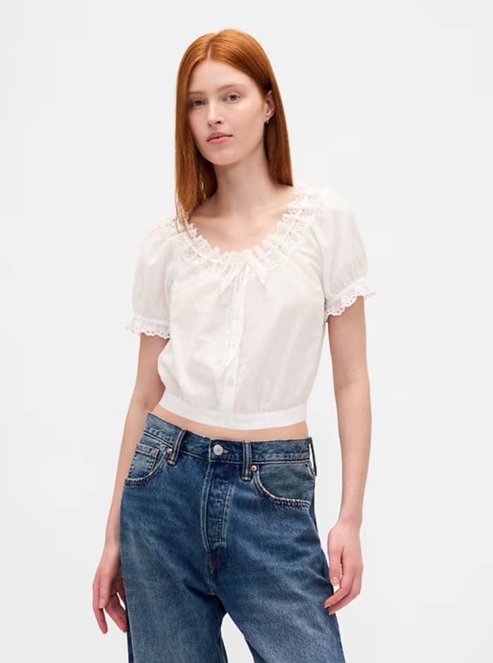 Person wearing a lace-trimmed achromatic blouse and jeans, posing against a plain background. Suitable for casual oregon relaxed buying looks