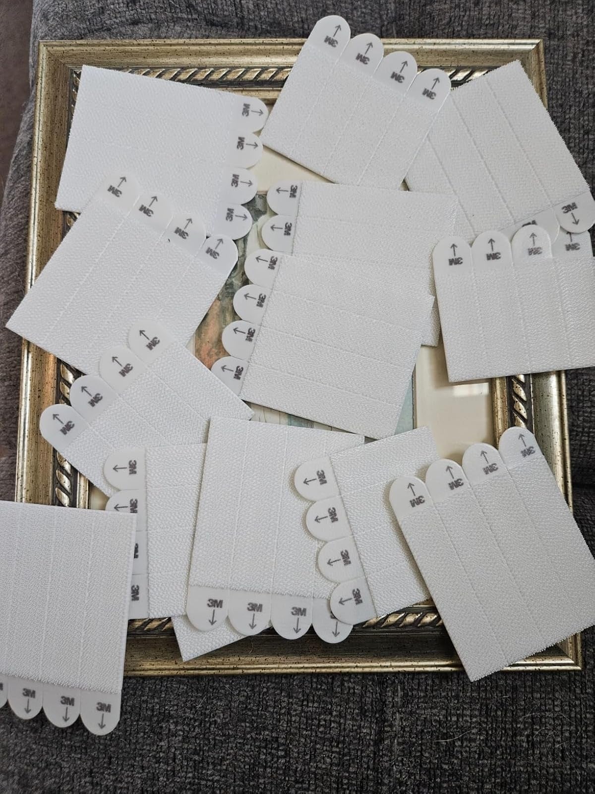 Adhesive partition  strips by 3M, displayed connected  a framed surface, perfect  for damage-free hanging