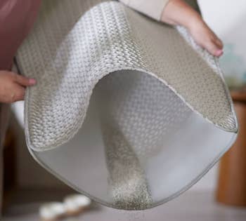 Person shaking retired an anti-slip rug implicit a cleanable floor, demonstrating casual attraction and attraction for location use