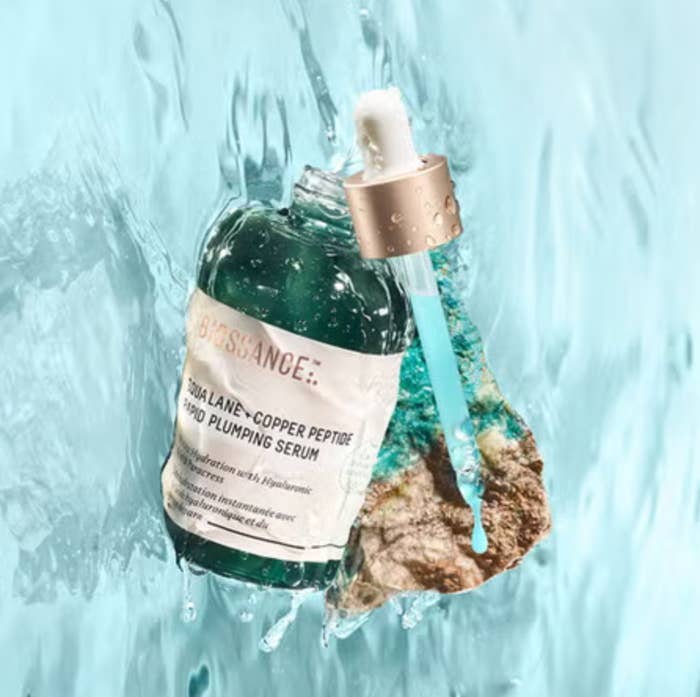 A vessel of skincare serum with a dropper surrounded by splashing water, highlighting hydration and freshness