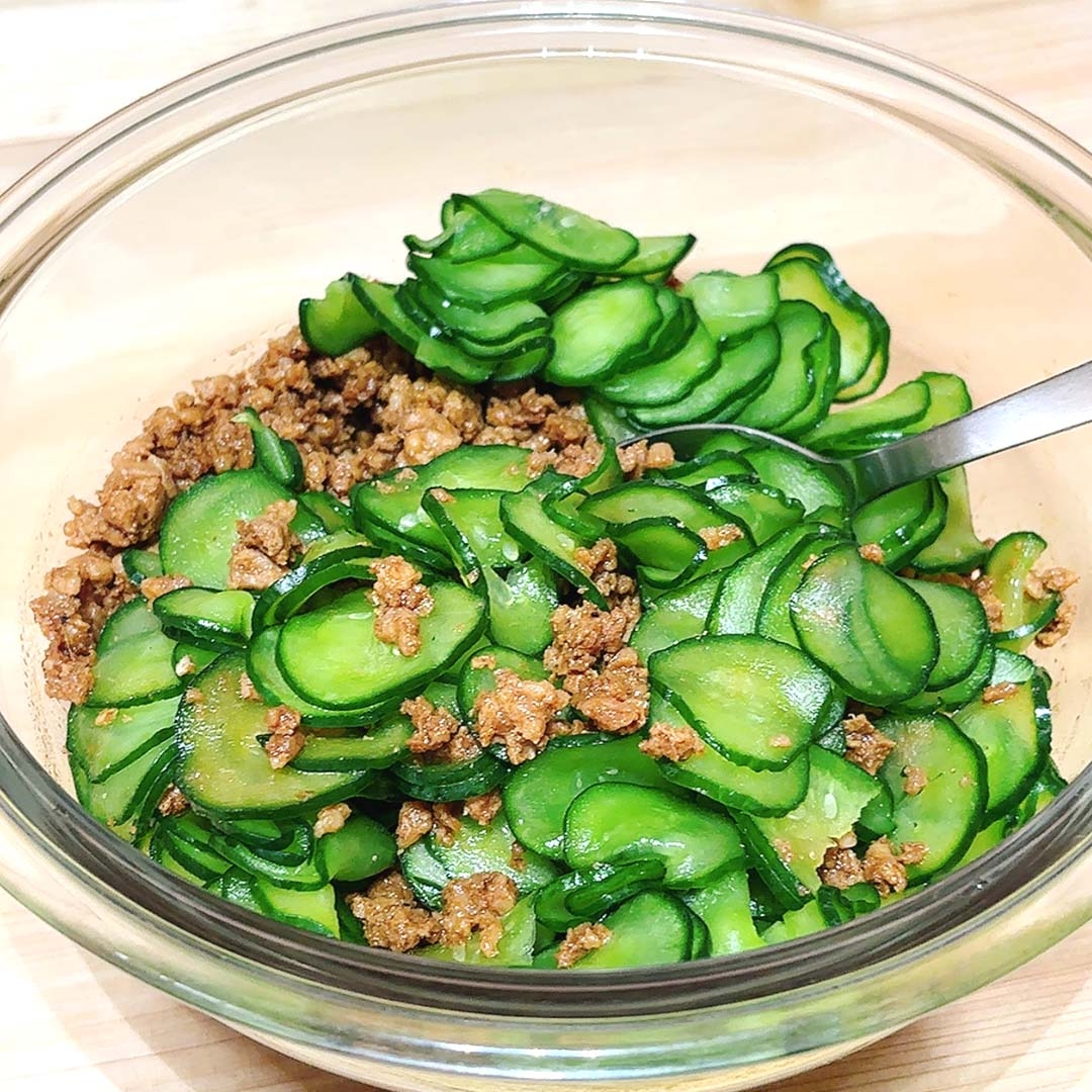 ガラスのボウルに入った薄くスライスされたきゅうりとひき肉のサラダ。シンプルでヘルシーな料理。