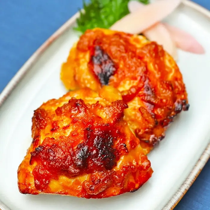 鶏むね肉のみそ漬け焼きが白い皿に盛られている。横に付け合せの野菜がある。