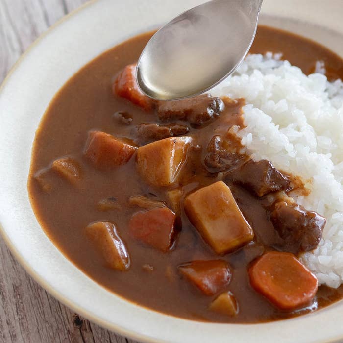 スプーンで盛り付けられた白米と一緒に、具がたっぷり入ったカレーが皿に盛り付けられている。