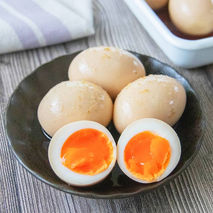 ゆずコショウとめんつゆで味付けされた味玉が小皿に盛られており、1個は半分に切られています。