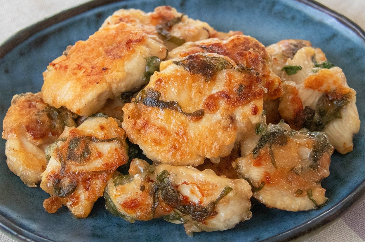 鶏むね肉を梅、大葉と一緒に焼いた料理が青い皿に盛られている。