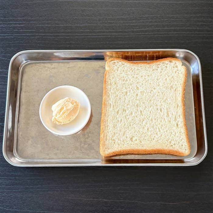 金属のトレイに食パンと小皿に盛られたバニラ味のアイスクリームが載っている。
