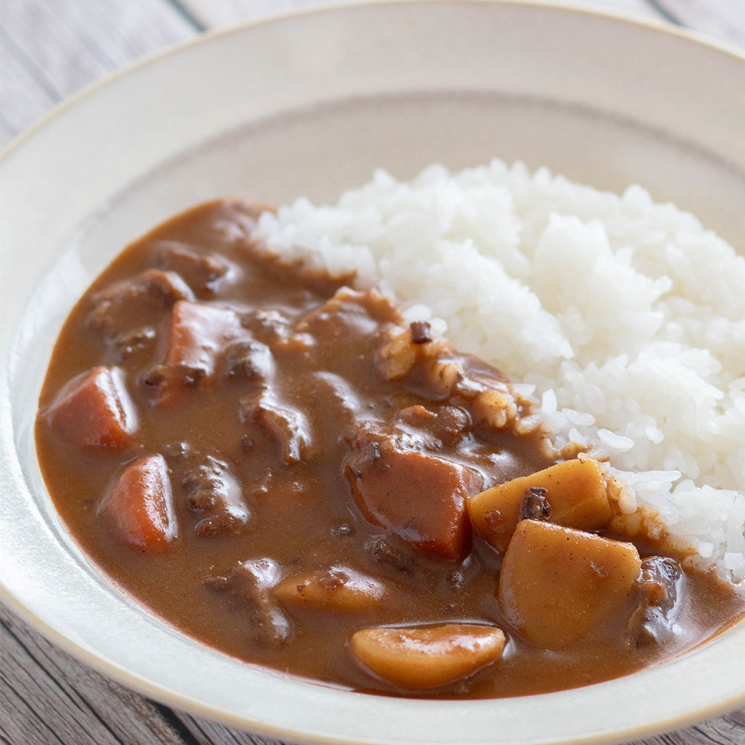 ご飯とカレーの皿、具材にジャガイモとニンジンが見える。