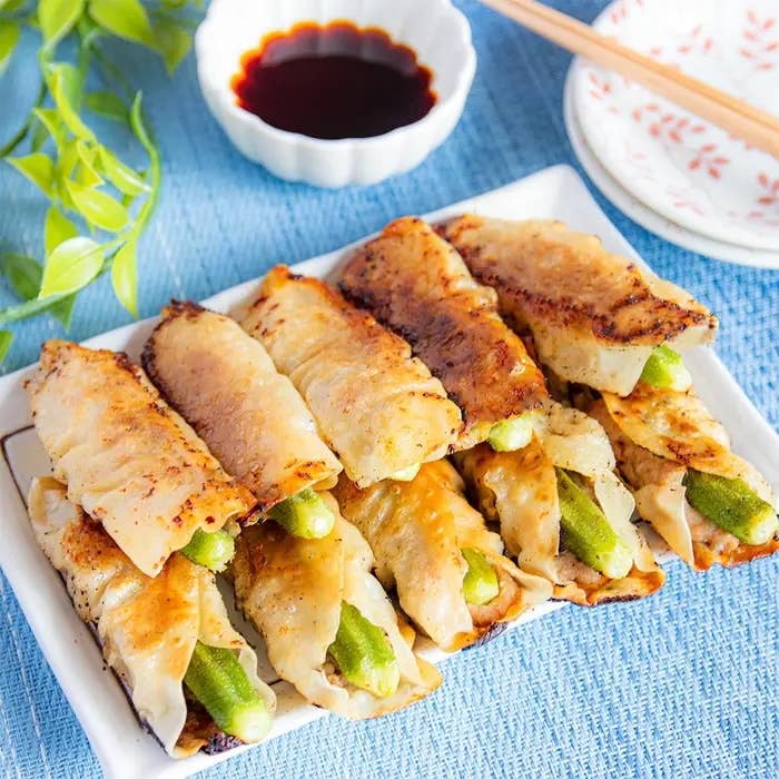 焼き色のついたギョーザが白い皿に盛られ、横に醤油の小皿が置かれている。