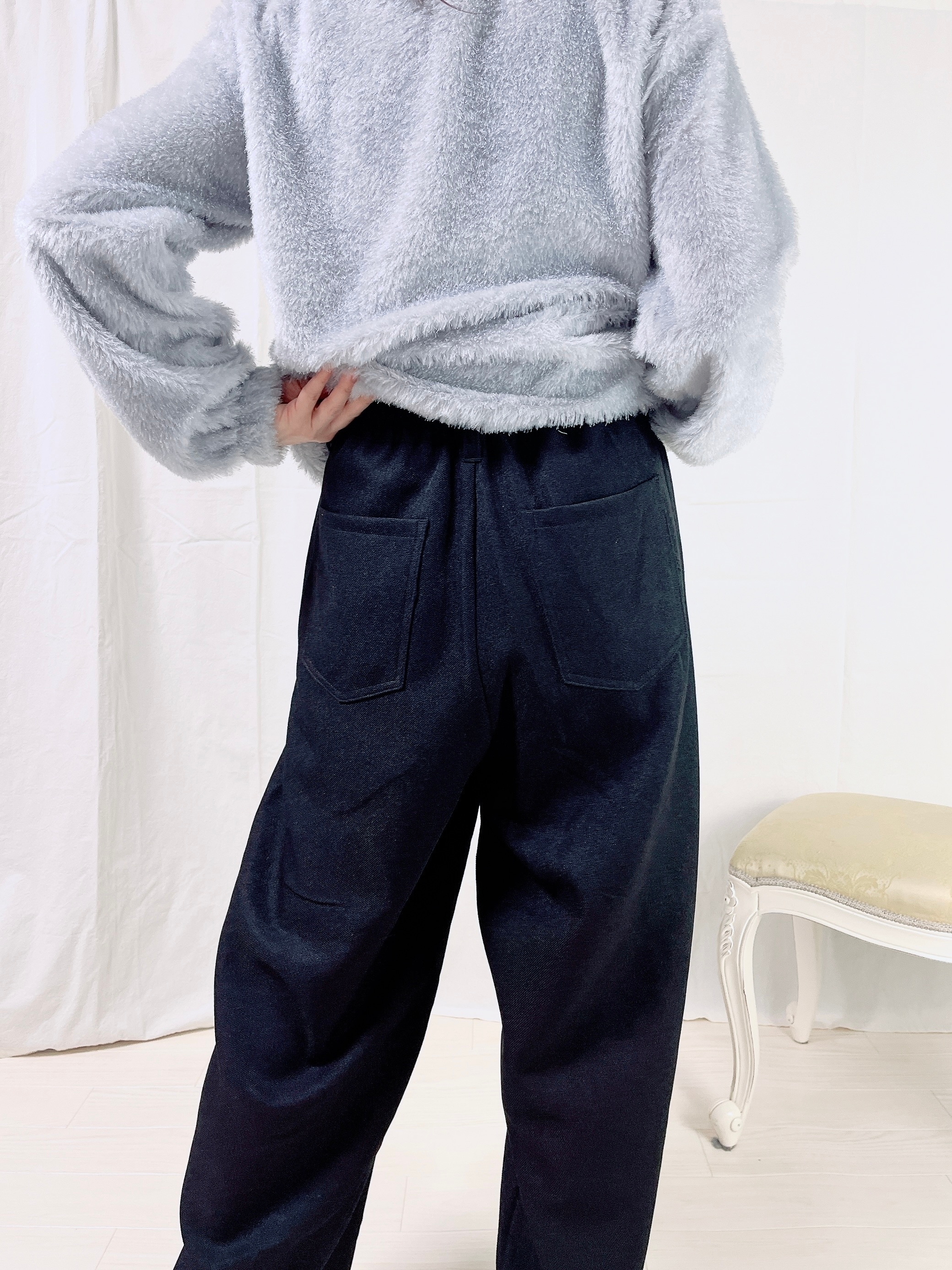 ふわふわしたセーターとゆったりしたパンツを着た人物が、スタイリッシュな後ろ姿を見せています。