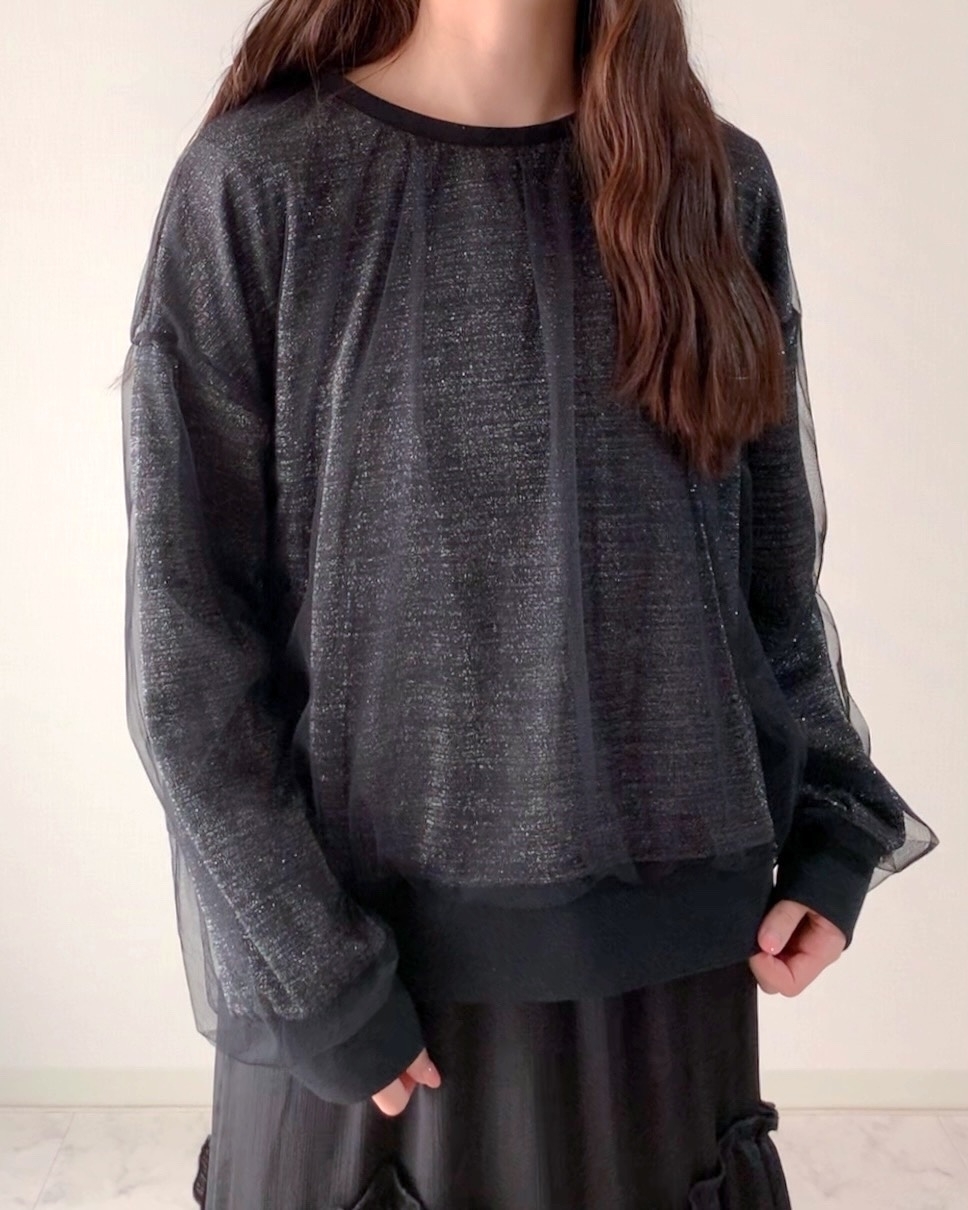 人物がシンプルな黒のトップスとスカートを着用し、カジュアルな装いをしています。