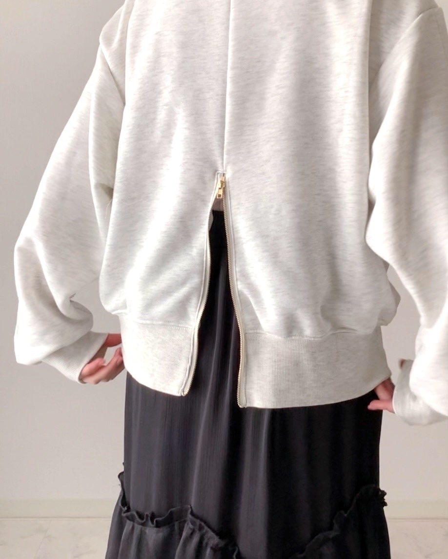 背中がジッパーで開いたユニークなデザインのジャケットを着た人。下にはフリルのスカートを着用。