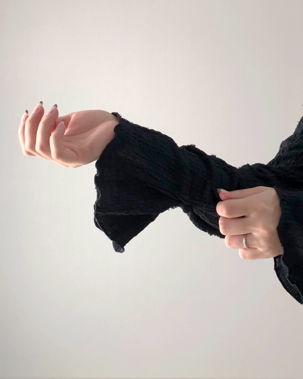 袖を整える人物の手元。指先の動きが見える。