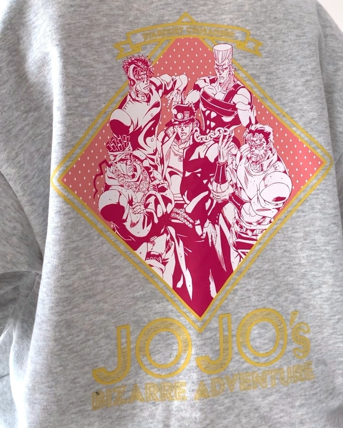 アニメ「ジョジョの奇妙な冒険」のキャラクターがプリントされたグレーのスウェット。