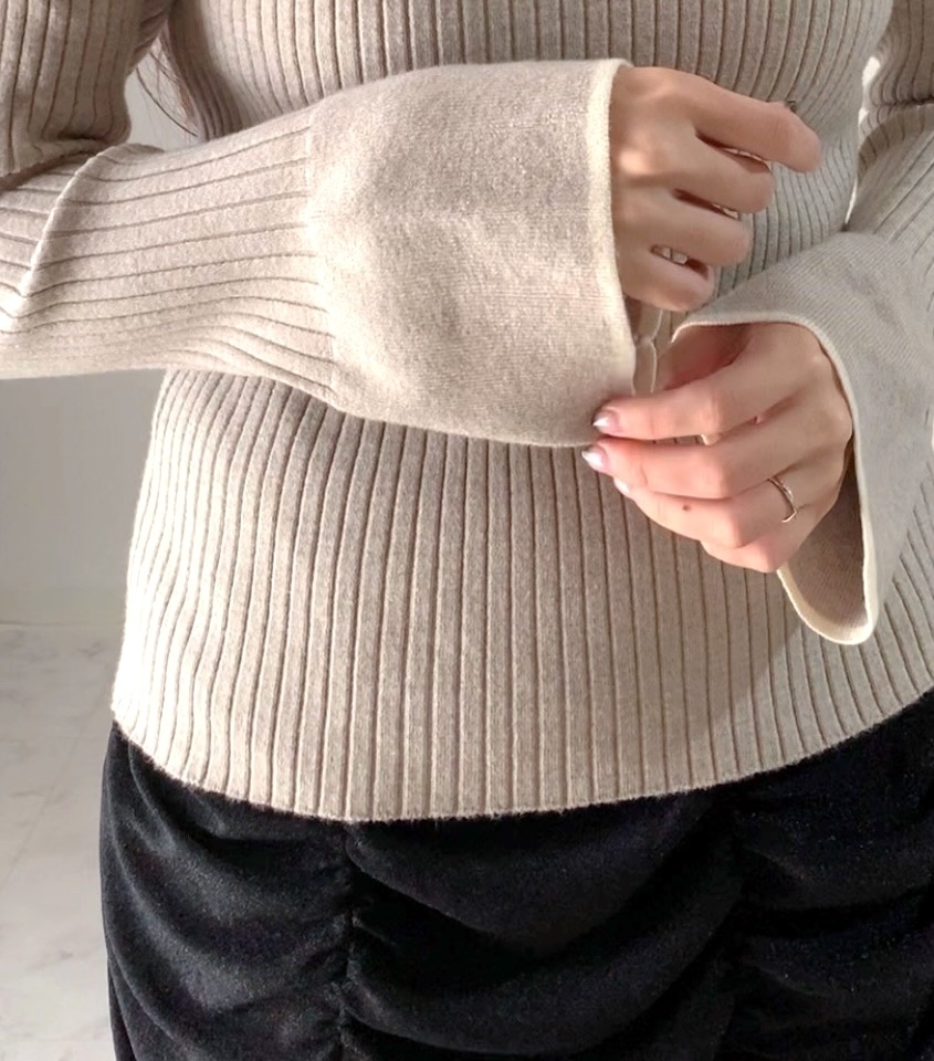 長袖のリブニットセーターとルーズフィットのパンツを着た人のトルソー部分。