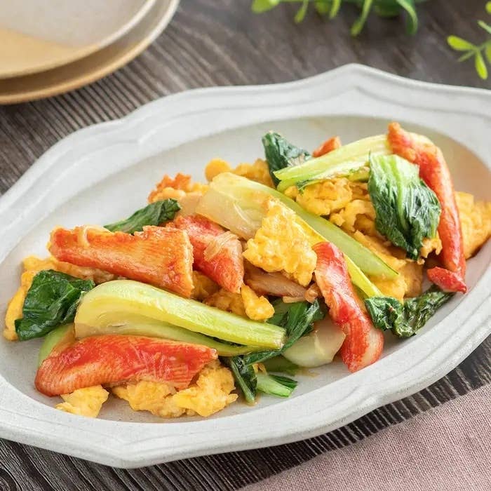 中華料理の盛り付け、カニ風味かまぼこ、卵、青菜が白い皿に載っている。