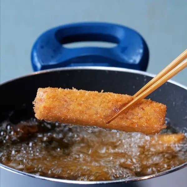 揚げ物を箸でつかむシーン。ポットで揚げられている様子。