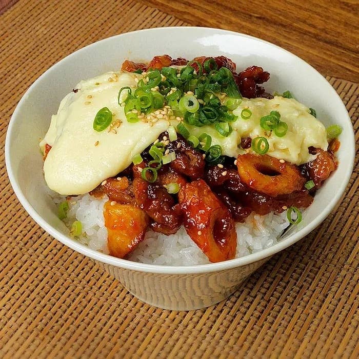 ご飯の上に甘辛い鶏肉とネギ、チーズソースがかかったどんぶり料理。