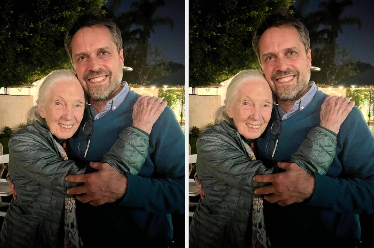 An elderly woman and a middle-aged man smile warmly, embracing in an outdoor setting. They appear happy and content