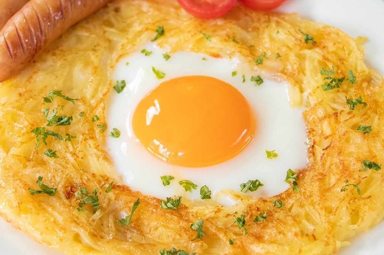 焼き上げたハッシュポテト目玉焼き、ソーセージ、ミニトマトが皿に盛り付けられている。