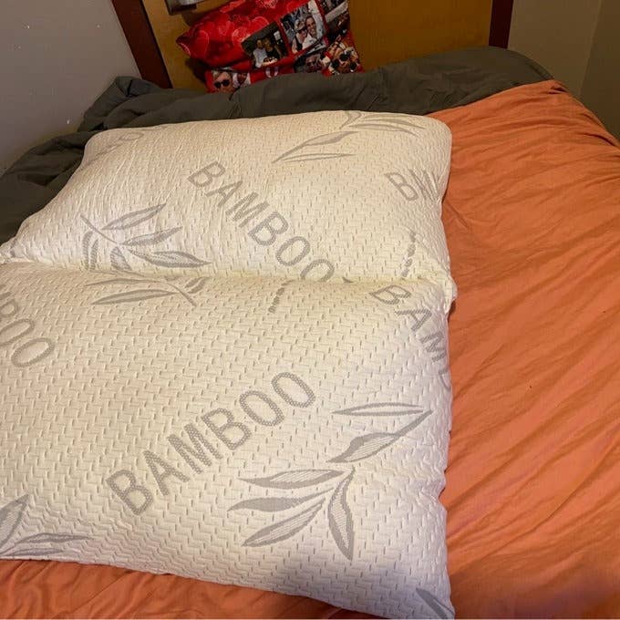 Bamboo pillows connected a neatly made furniture with an orangish duvet
