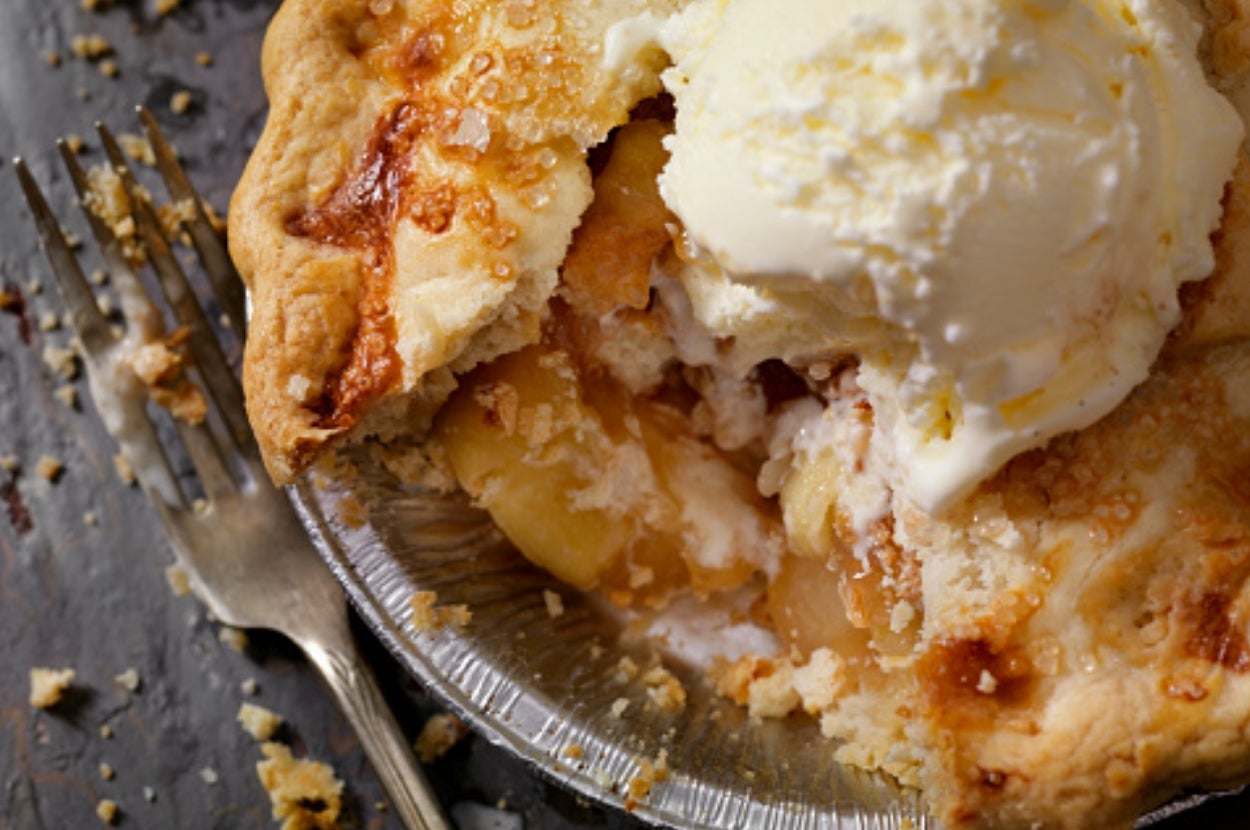 Close-up of a partially eaten apple pie with a scoop of vanilla ice cream on top, sitting next to a fork