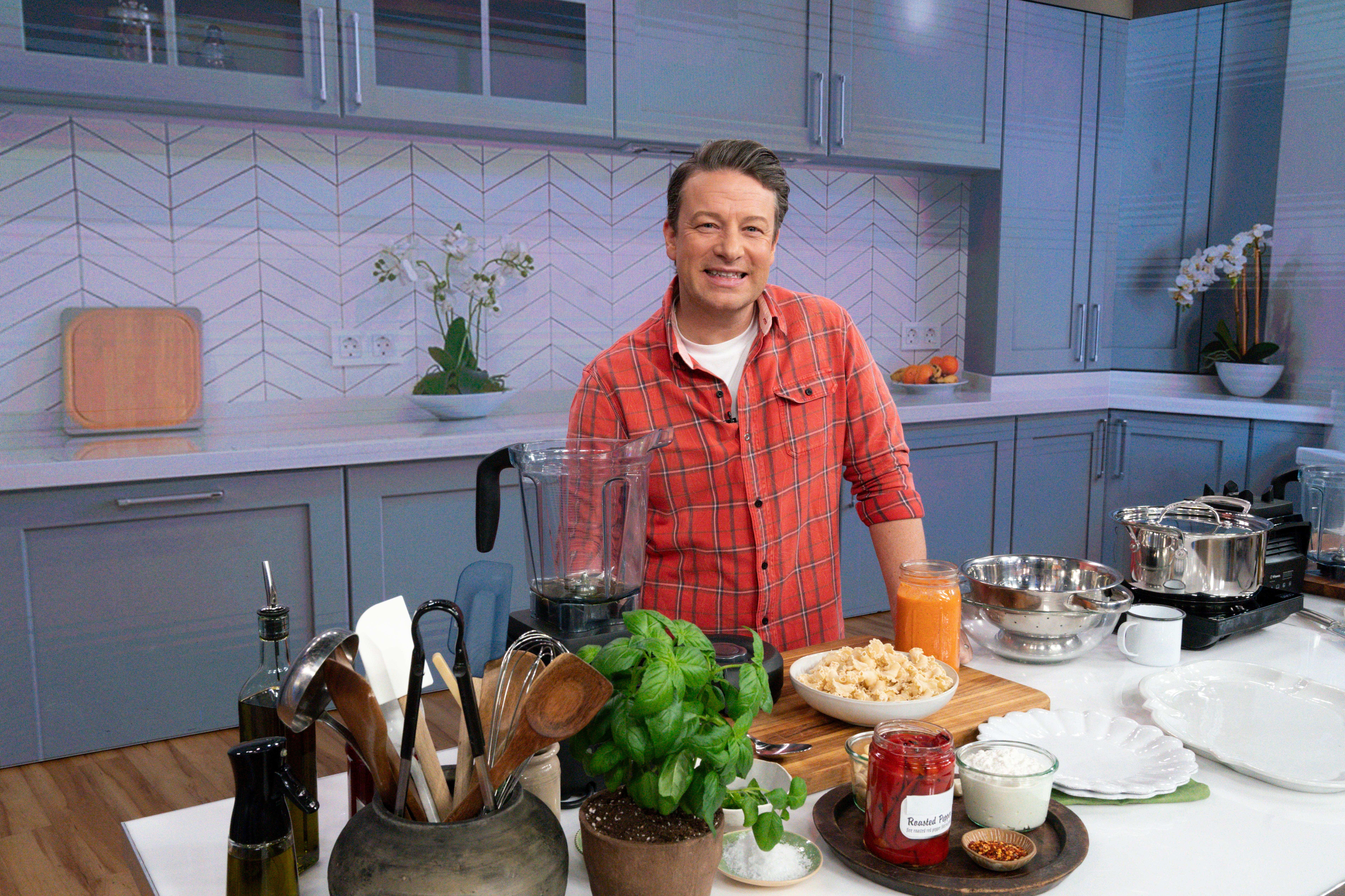 Person in a kitchen wearing a plaid shirt, standing behind a counter with cooking ingredients and utensils