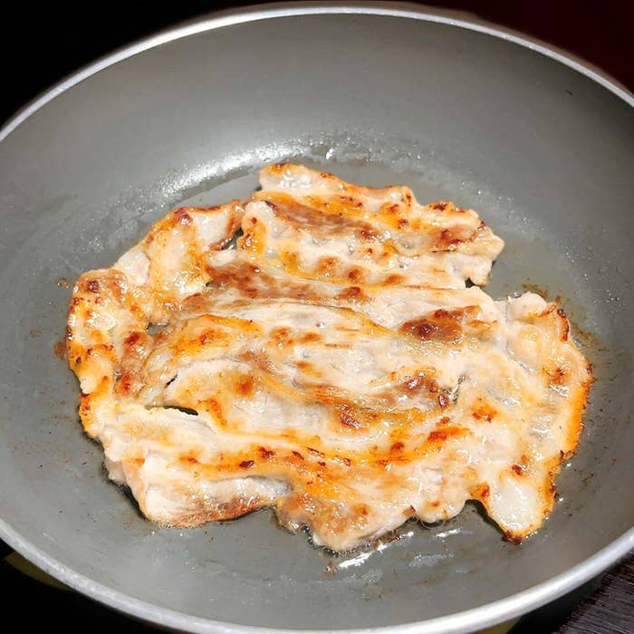 フライパンで焼かれている薄切りの豚肉。ジューシーで香ばしい焼き目がついている。