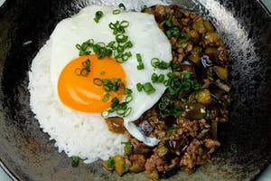ご飯、目玉焼き、肉と野菜炒めが盛られた美しいプレート料理。緑のネギがトッピングされている。