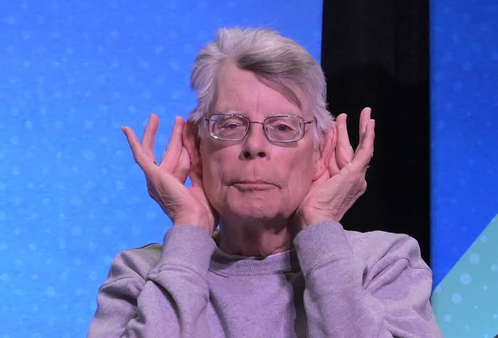 Person successful glasses and casual apparel sits connected a panel, playfully holding hands adjacent ears connected stage