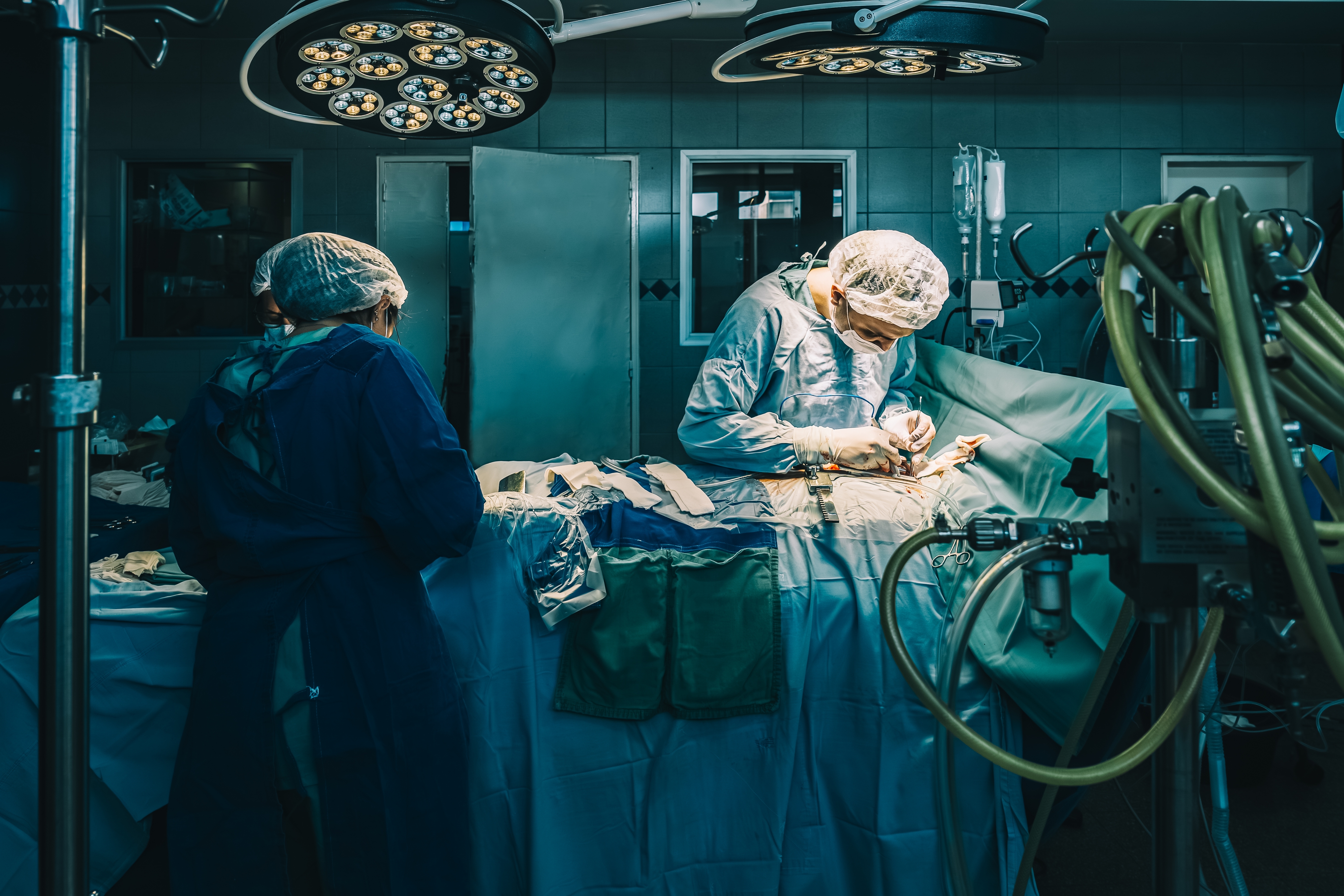 Kirurger som utfører en operasjon i et velutstyrt operasjonsrom, og fokuserer intenst på prosedyren. Medisinske verktøy og lys er synlige