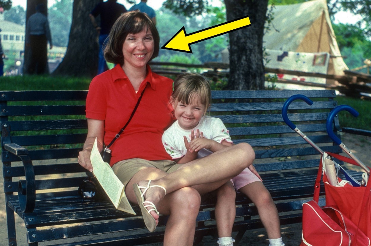 Smiling woman in casual summer outfit sitting on a bench, holding a paper, with a child beside her and a stroller nearby. Arrow pointing to the woman
