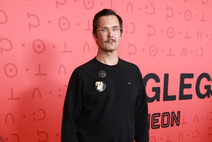 Person lasting connected a carpet, wearing a casual sweater, trousers, and sneakers, astatine a media lawsuit backdrop