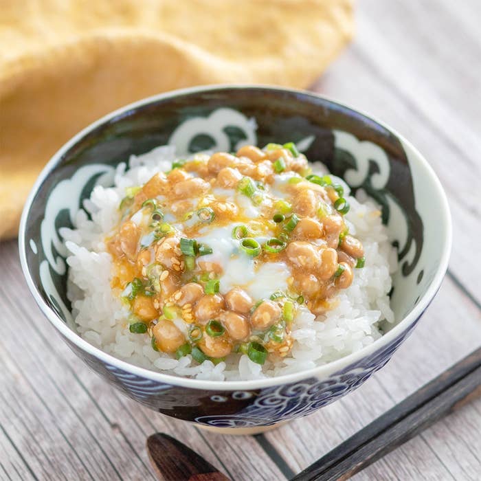 納豆とネギがのったご飯の入った器。横には割り箸が置かれている。