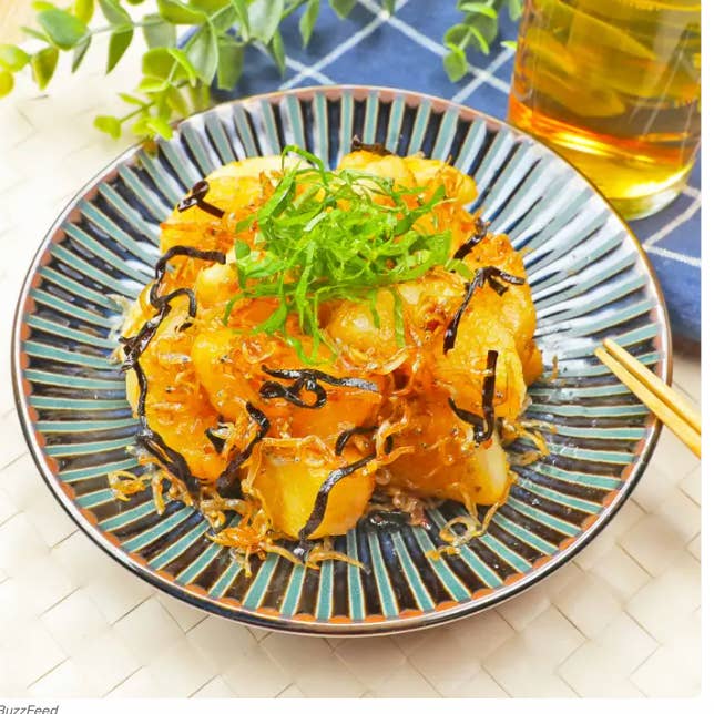 和風の揚げじゃがいも炒めが皿に盛られている。刻みネギと海苔がトッピングされており、横に飲み物がある。