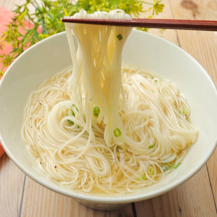 麺鉢から上げられたそうめんを箸で持ち上げているシンプルな食事シーン。