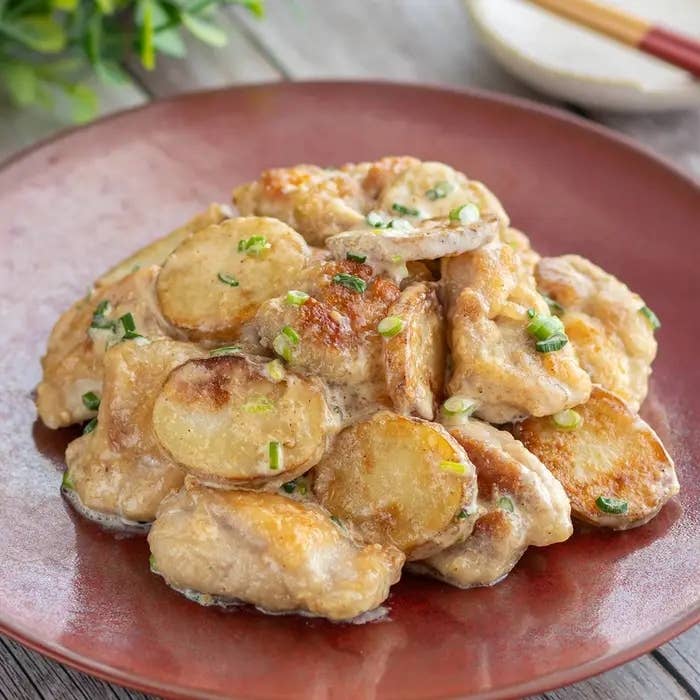 皿に盛られたクリーミーなソースで調理された鶏肉料理。ネギがトッピングされています。