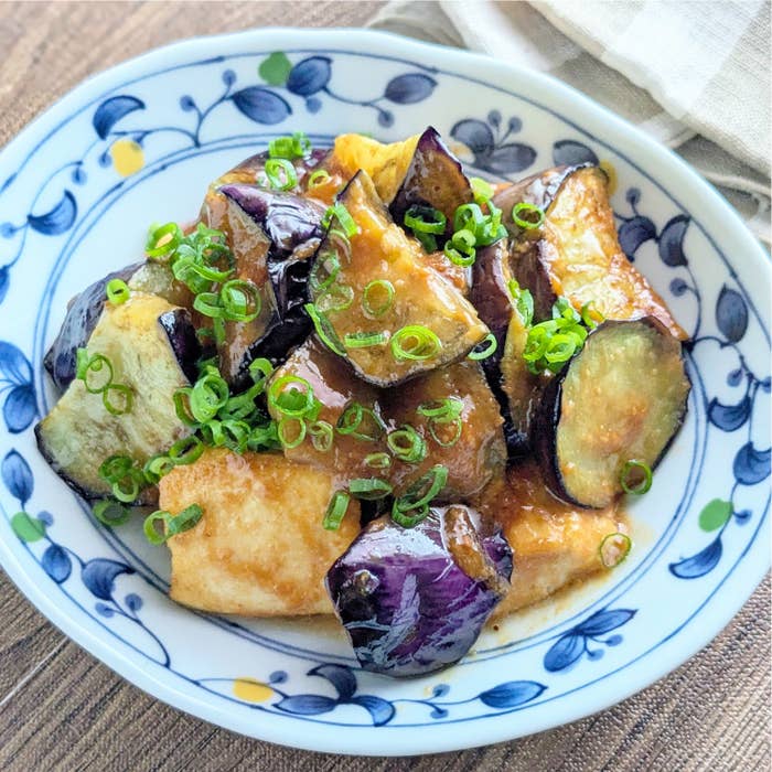 皿に盛られたナスと豆腐の炒め物。青ネギが上にのっている。